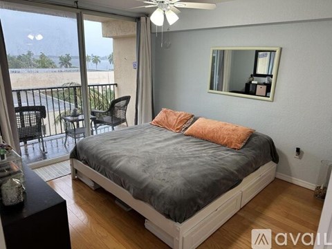 A bedroom with a large bed and a balcony overlooking the beach.