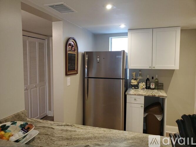 A kitchen with a stainless steel refrigerator and white cabinets.