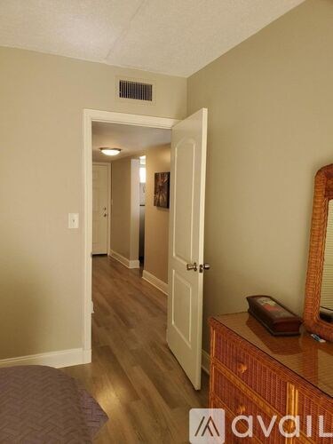A hallway with a white door and a brown dresser.