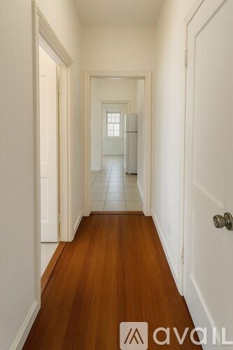 A hallway with wood floors and white walls.