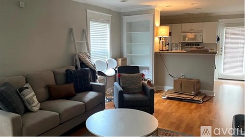 A living room with a grey couch, a white coffee table, and a grey armchair.