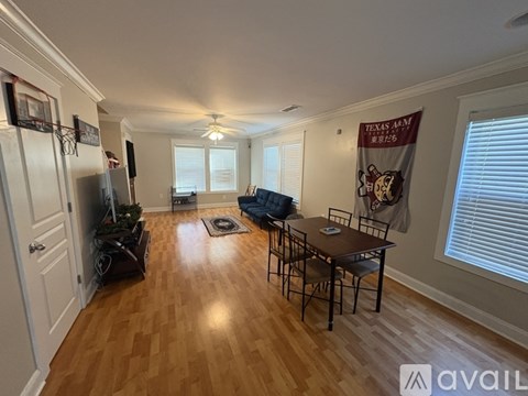 A living room with a wooden floor and a Texas A&M banner on the wall.
