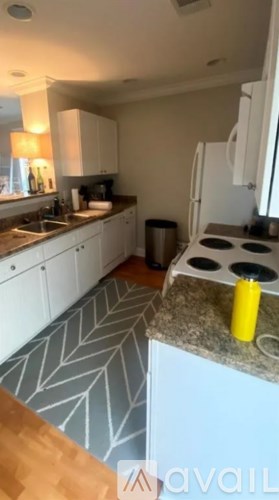 A kitchen with a white fridge, a sink, and a stove top.