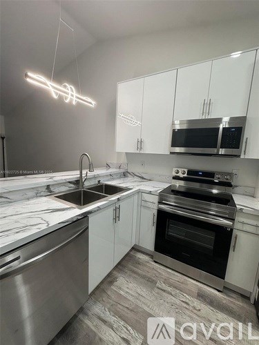A modern kitchen with a marble countertop and stainless steel appliances.