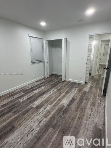 A room with wooden flooring and white walls.
