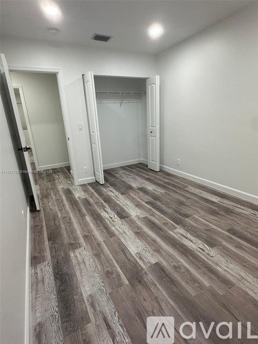 A room with wooden flooring and three open doors.