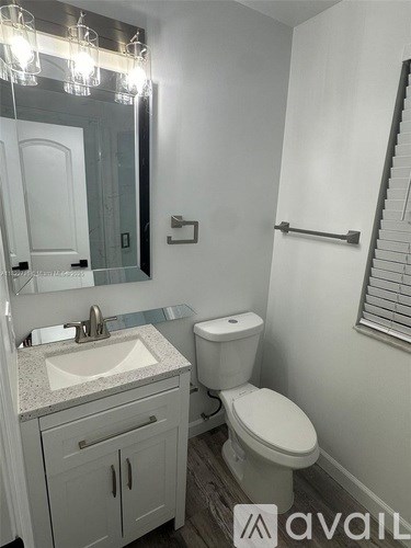 A bathroom with a toilet, sink, and mirror.