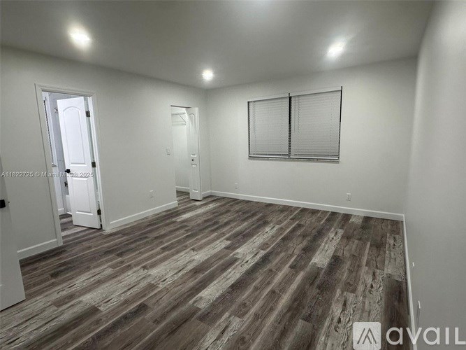 A room with wooden flooring and white walls.