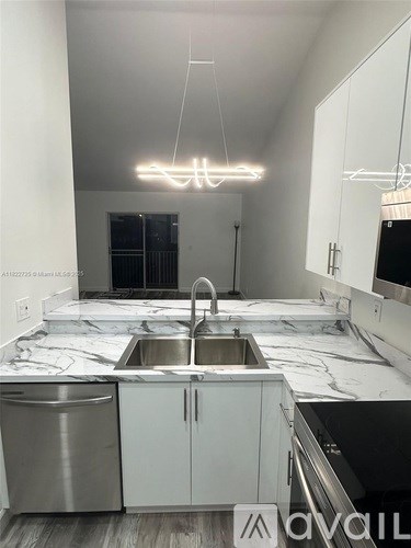 A modern kitchen with white cabinets and marble countertops.
