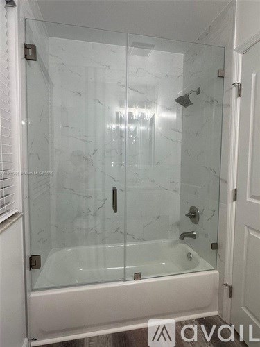 A white bathroom with a glass shower door and tub.