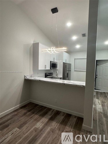 A modern kitchen with a large island and a hanging light fixture.