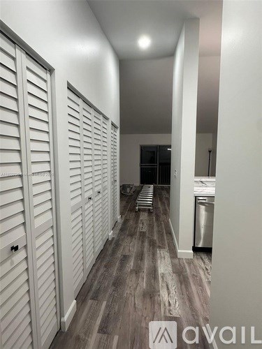 A hallway with white walls and wood flooring with a logo that says "avai" on the bottom right.