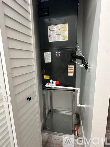 A black fridge with a white door and a white wall behind it.