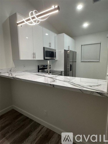 A kitchen with white cabinets and a marble countertop.