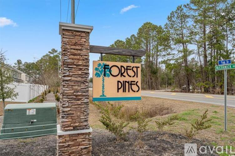 A sign for Forest Pines stands in front of a stone pillar.
