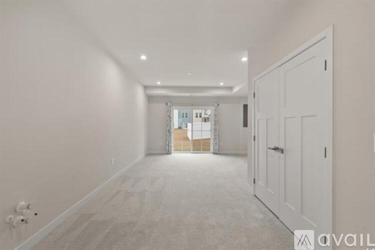 A spacious room with a carpeted floor and white walls.