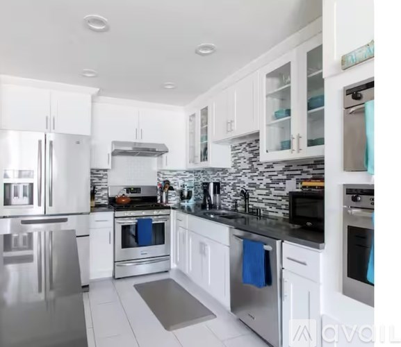 A modern kitchen with white cabinets and stainless steel appliances.