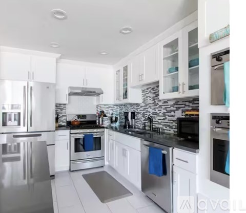 A modern kitchen with white cabinets and stainless steel appliances.