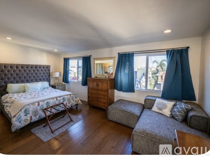 A bedroom with a bed, a couch, and a chair.