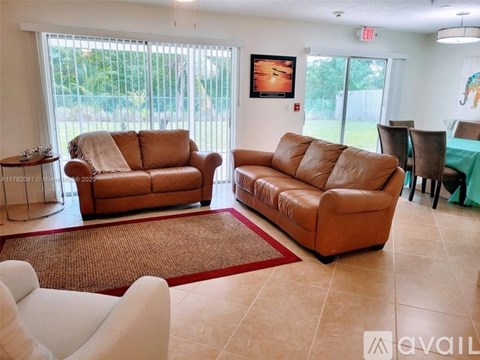 Two tan couches in a living room with a red rug in front of them.
