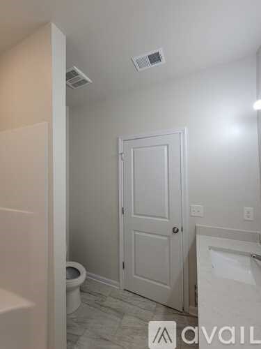 A bathroom with a toilet, sink, and a door.