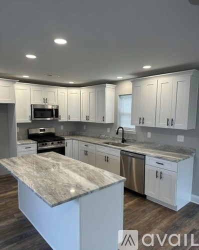 A kitchen with white cabinets and a marble island.