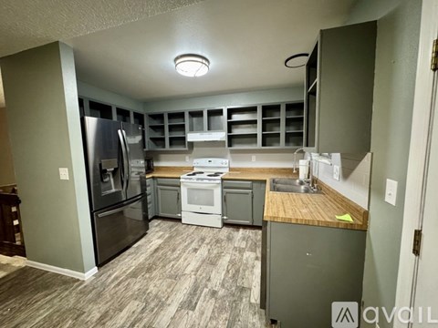 A kitchen with a refrigerator, oven, and sink.