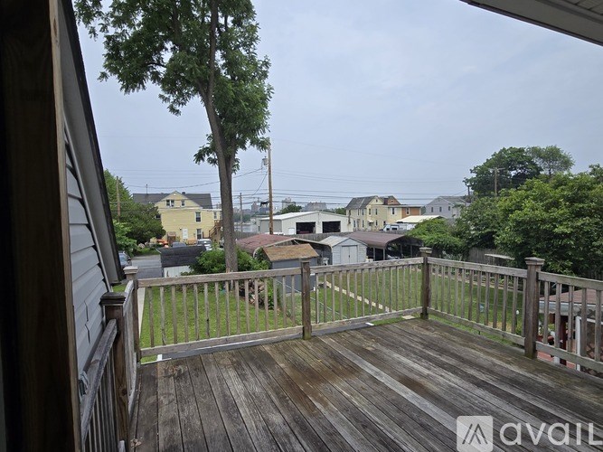 A wooden deck with a railing and a view of a street with houses.