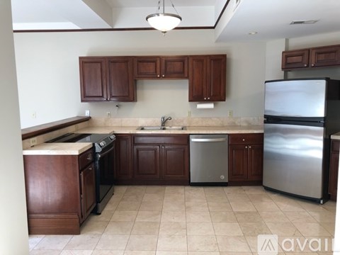 A kitchen with brown cabinets and a stainless steel refrigerator.