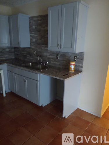A kitchen with a stone backsplash and white cabinets.