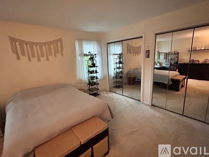 A bedroom with a bed and a mirrored wall.