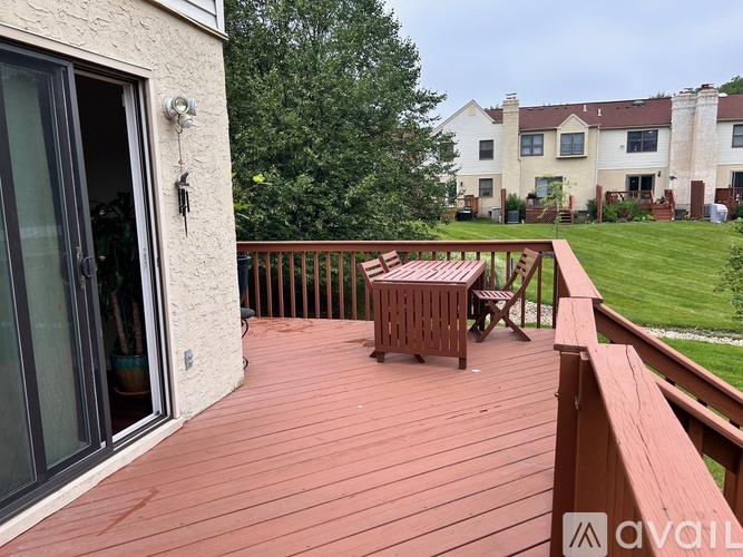A wooden deck with a table and chairs overlooking a grassy area.