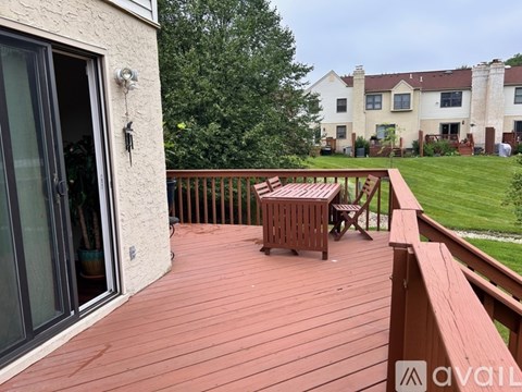 A wooden deck with a table and chairs overlooking a grassy area.