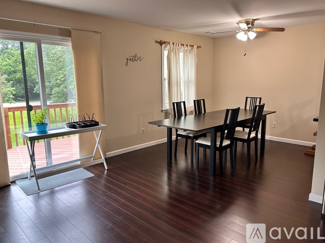 A dining room with a table and chairs and a sliding glass door.