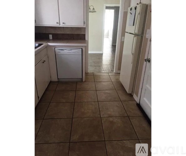 A kitchen with brown tiles and white appliances.