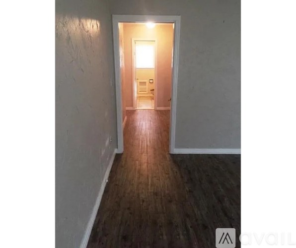 A hallway with wooden floors and a doorway leading to another room.