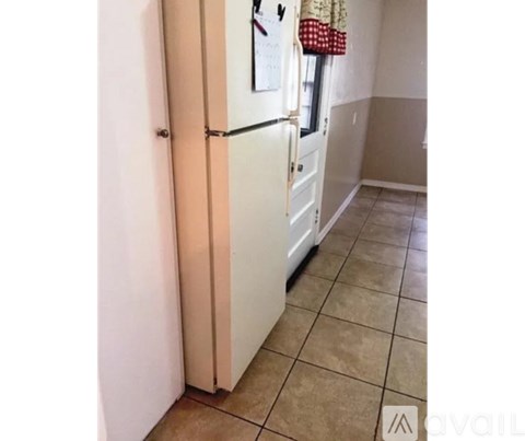 A white refrigerator in a kitchen with a checkered floor.
