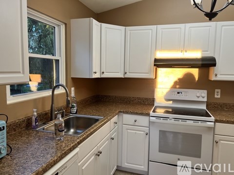 A kitchen with white cabinets and a stove top oven.