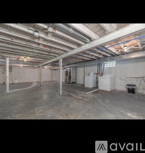A spacious room with a concrete floor and exposed ceiling pipes.