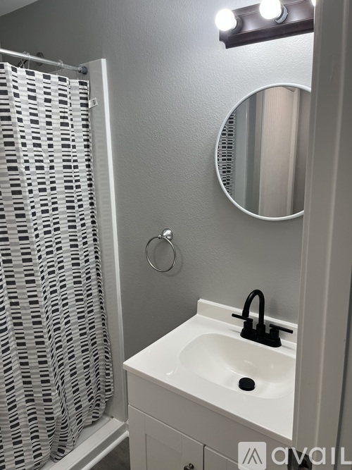 A bathroom with a white sink and a round mirror.