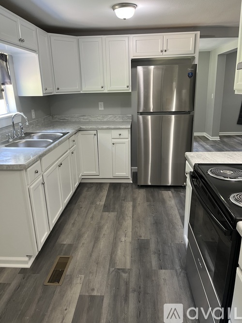 A kitchen with a stainless steel refrigerator and a stove top oven.