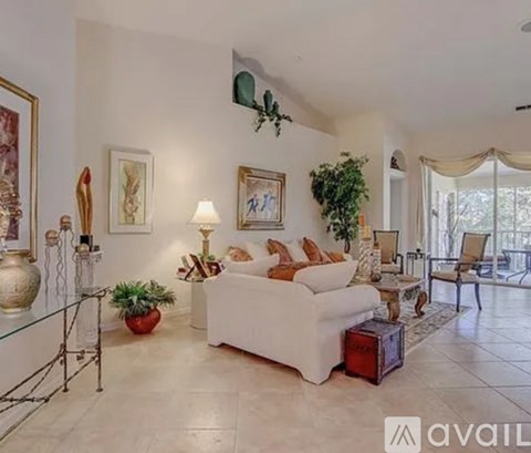 A living room with a white couch, a glass table, and a painting on the wall.