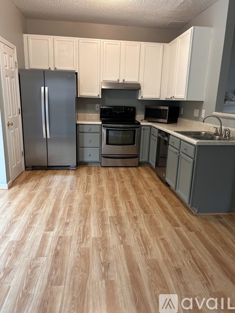 A kitchen with wooden floors and white cabinets.