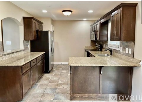 A kitchen with brown cabinets and a black refrigerator.