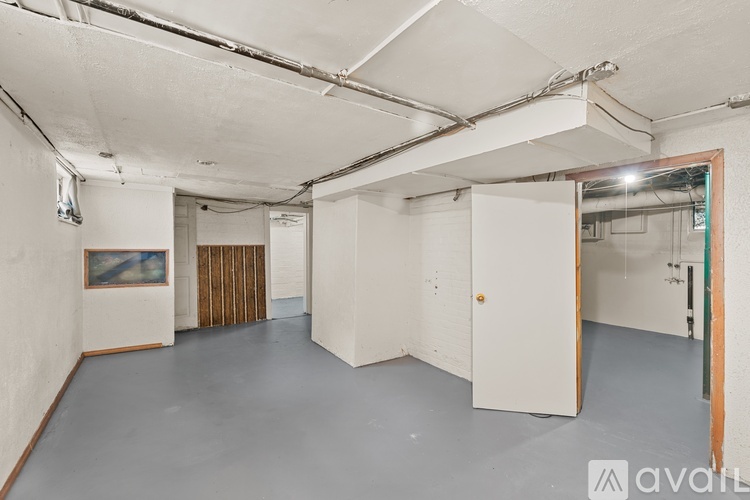 A spacious empty room with a painting on the wall and a door on the right.