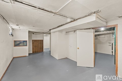 A spacious empty room with a painting on the wall and a door on the right.