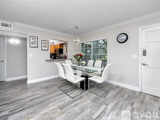 A dining room with a glass table and white chairs.