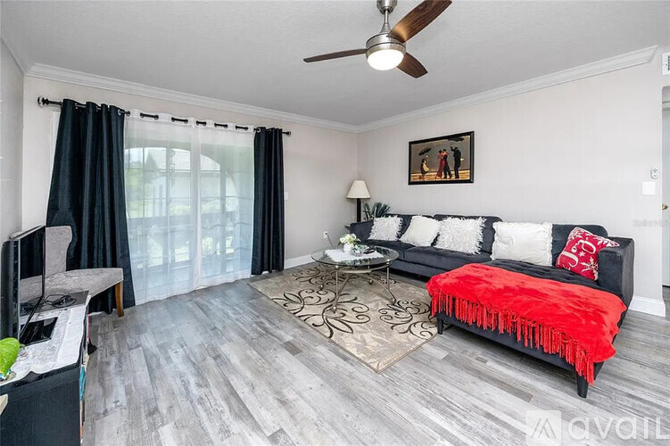 A living room with a black and white couch and a red throw on it.