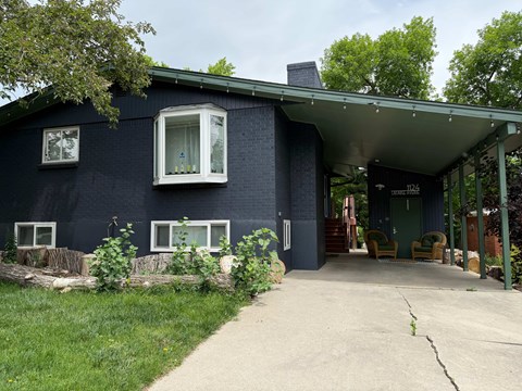 A blue house with a white window and a green door.