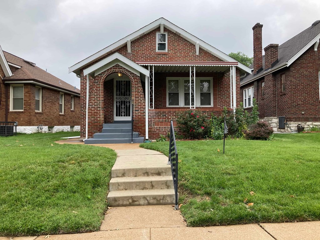 A brick house with a front porch and a small front yard.